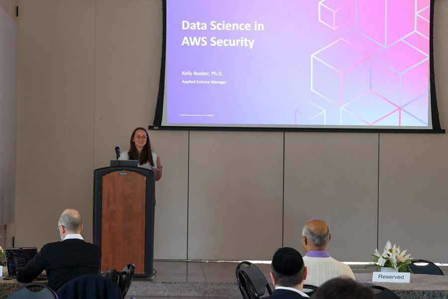 Kelly Rooker, Applied Science Manager, AWS Security, stands at a podium onstage to present the AWS Security team's overview and topics of interest.