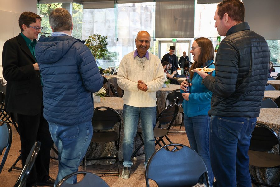 Sanjeev Khudapur, AI2AI Initiative Director, JHU, and Kelly Rooker, Applied Science Manager, AWS Security, laugh while enjoying conversation with others at the event.